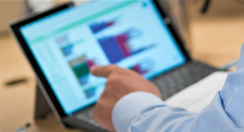 stock photo of person pointing to their laptop screen showing data visualizations
