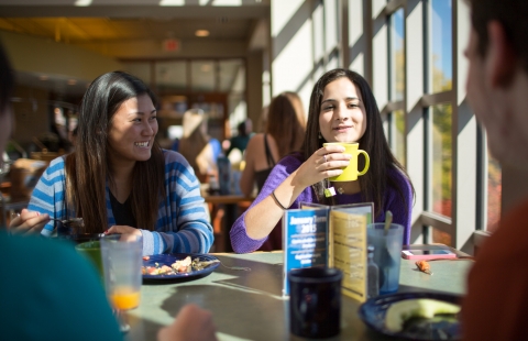 A photo of college students laughing and having coffee together