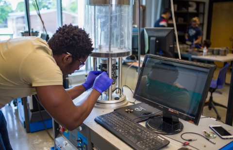A photo of a Black male college student working in a laboratory 